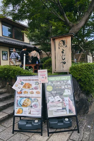 木の看板の立つ店先と、写真入りの品書きの立て看板