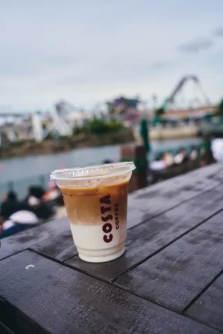 水辺のテーブルに置かれた、アイスカフェラテのカップ