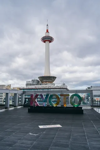 曇り空に立つ白い塔と、屋上に置かれた色とりどりの文字のオブジェ