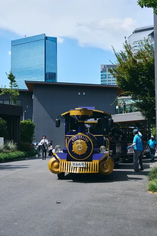 汽車の形をした園内の乗り物と、背後の高層ビル