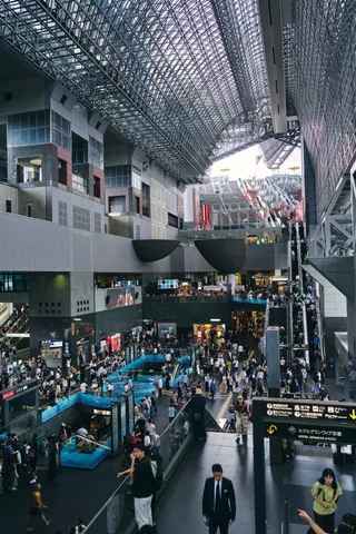 大きな吹き抜けと鉄骨の屋根の下、人で賑わう駅ビル