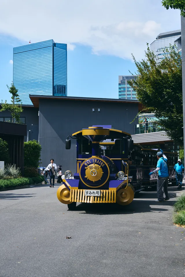 汽車の形をした園内の乗り物と、背後の高層ビル